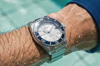 Montre étanche portée sous l'eau dans une piscine, gros plan sur le cadran et la couronne en acier inoxydable