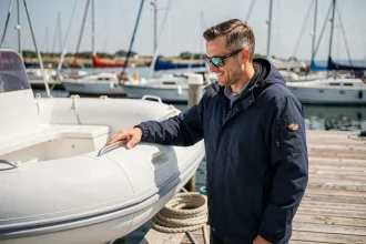 Passionné de semi-rigide inspectant la coque de son pneumatique sur un ponton de port de plaisance